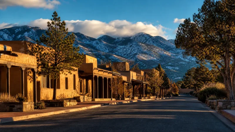 High-desert town street of earth-toned adobe-style buildings with mountains behind, Santa Fe County Business License